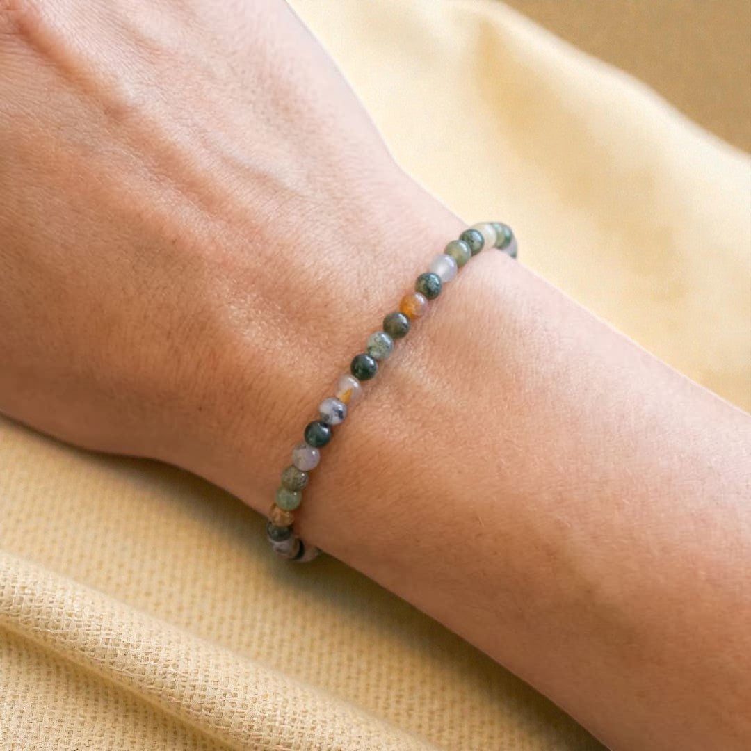 Atelier Tibet delicate bracelet with 4mm natural stone beads in green, white, and orange hues, strung on elastic.
