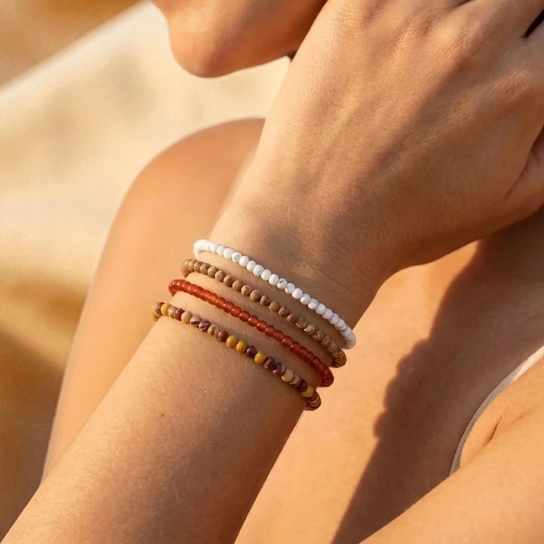 Atelier Tibet stackable bracelets with 4mm natural stone beads in white, red, brown, and yellow.
